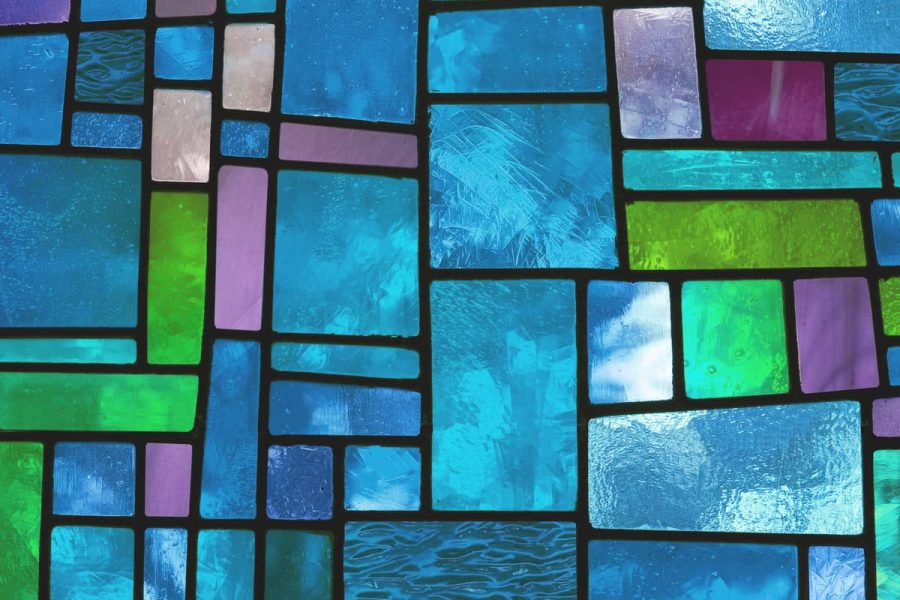 "Image of a multicolored stained glass window with irregular block pattern in a hue of blue, square format"